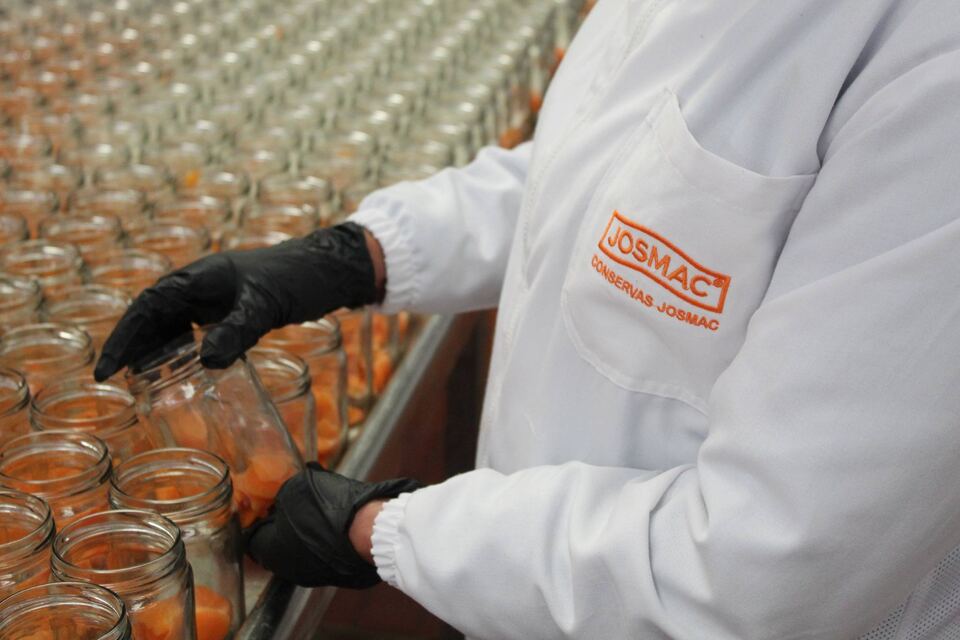 Operario de Josmac envasando producto en frascos de vidrio en la línea de llenado.